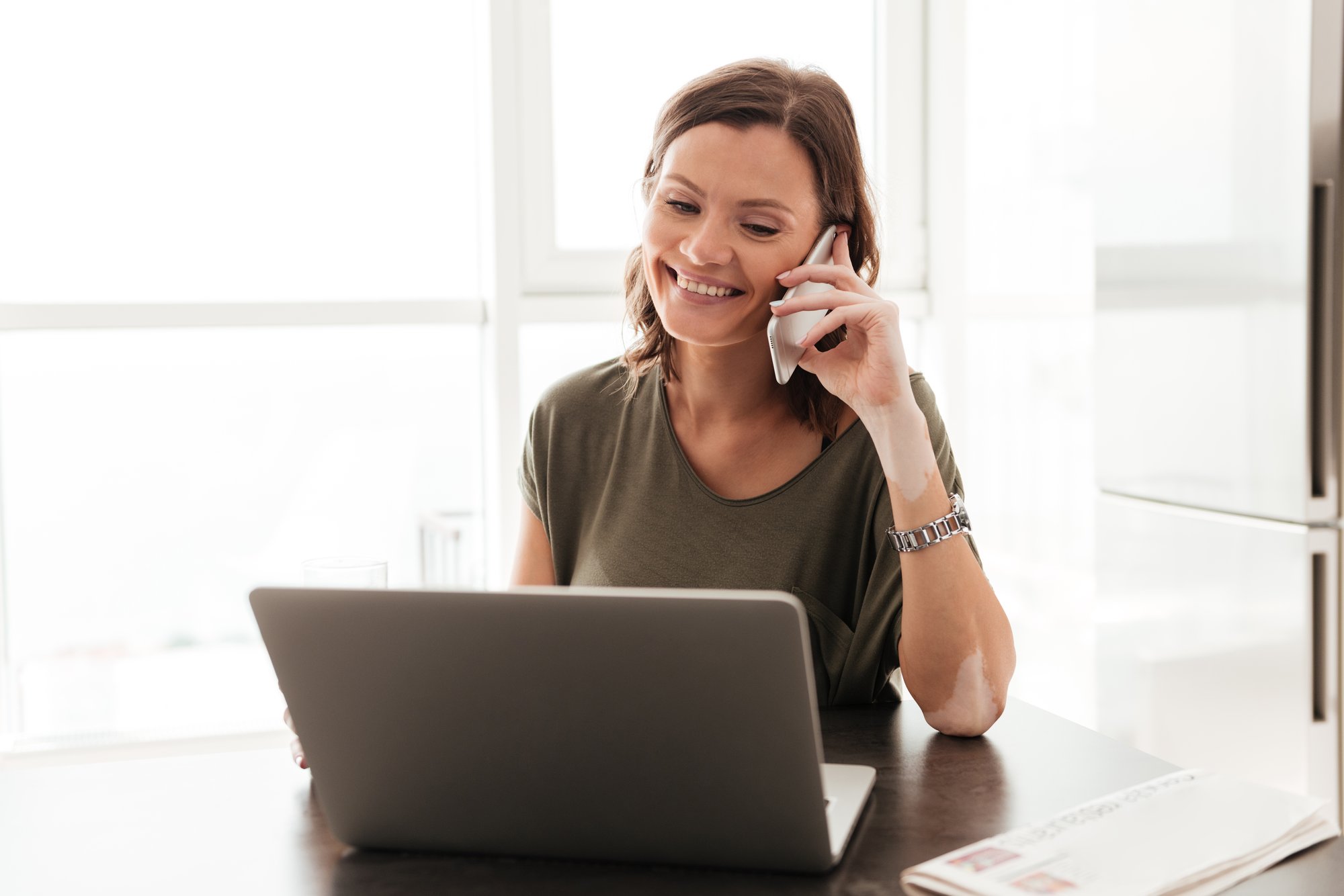 feliz-mujer-casual-hablando-telefono-inteligente-mientras-sentado-cerca-mesa-computadora-portatil feliz-mujer-casual-hablando-telefono-inteligente-mientras-sentado-cerca-mesa-computadora-portatil